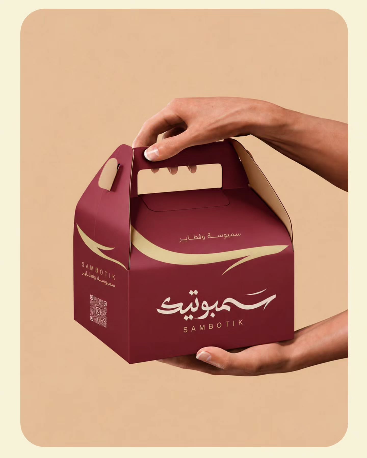 عرض علبة سمبوتيك العنابية ذات المقبض بين يدين على خلفية خوخية.